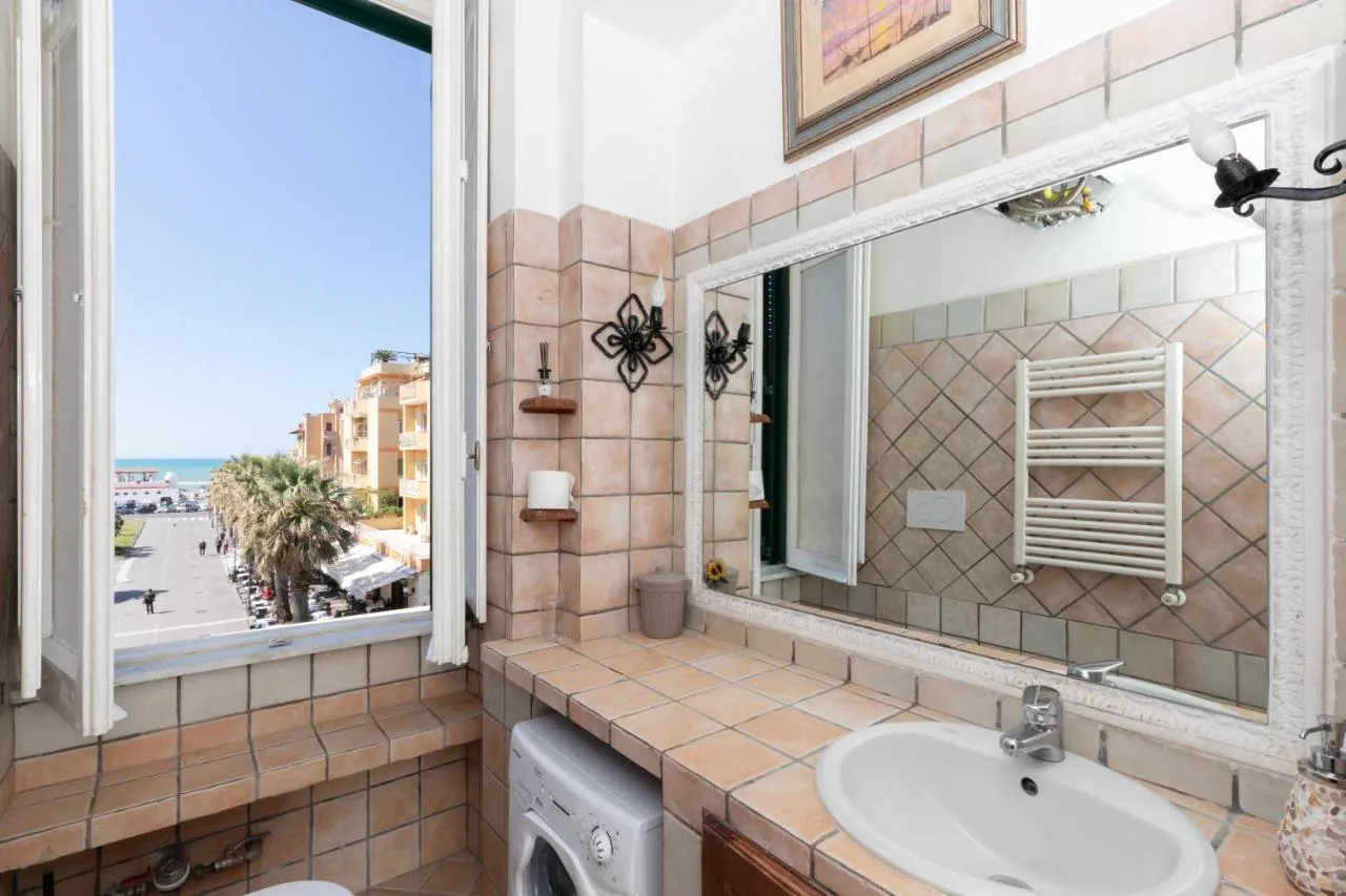 Anco Marzio House — Il bagno con il lavabo in maiolica e la finestra sul lungomare